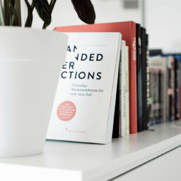 Topf-Pflanze vor einer Reihe Design-B&uuml;cher auf einem Schrank